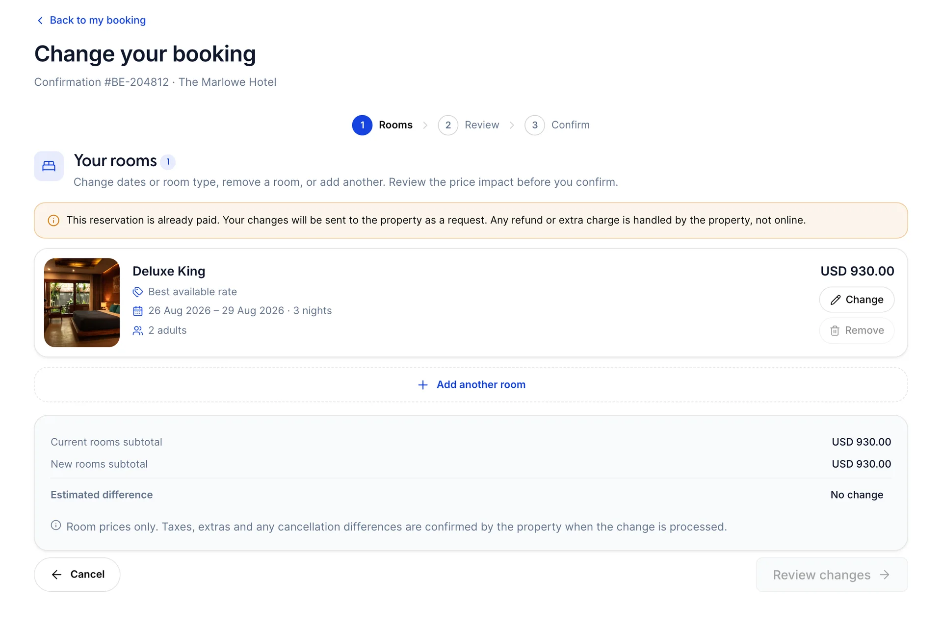 The Change your booking wizard on step 1 of 3, headed Rooms, with Review and Confirm ahead of it. An amber notice says the reservation is already paid and changes will be sent to the property as a request. A Deluxe King on Best available rate for 26 to 29 Aug 2026 shows USD 930.00 with Change and Remove buttons, an Add another room row sits below it, and a summary compares the current and new rooms subtotal with an Estimated difference of No change.