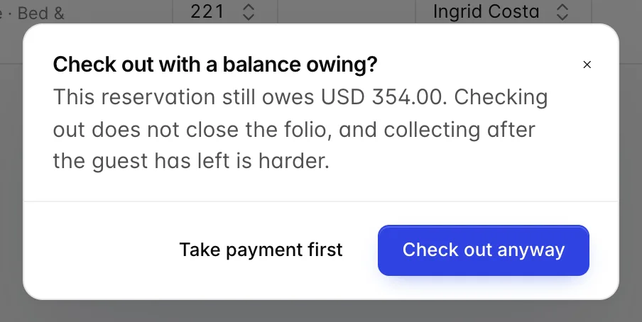 Une boîte de dialogue intitulée « Check out with a balance owing ? » (Avez-vous une réservation avec un solde impayé ?) expliquant que la réservation présente encore un solde impayé de 354,00 USD et que la vérification de l’out ne clôture pas le folio, avec les boutons « Take payment first » (Vérifier le solde) et « Check <span translate="no">out anyway</span> » (Vérifier la réservation).